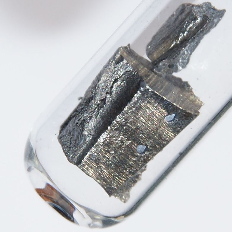 Shiny pieces of elemental neodymium metal sealed under argon.